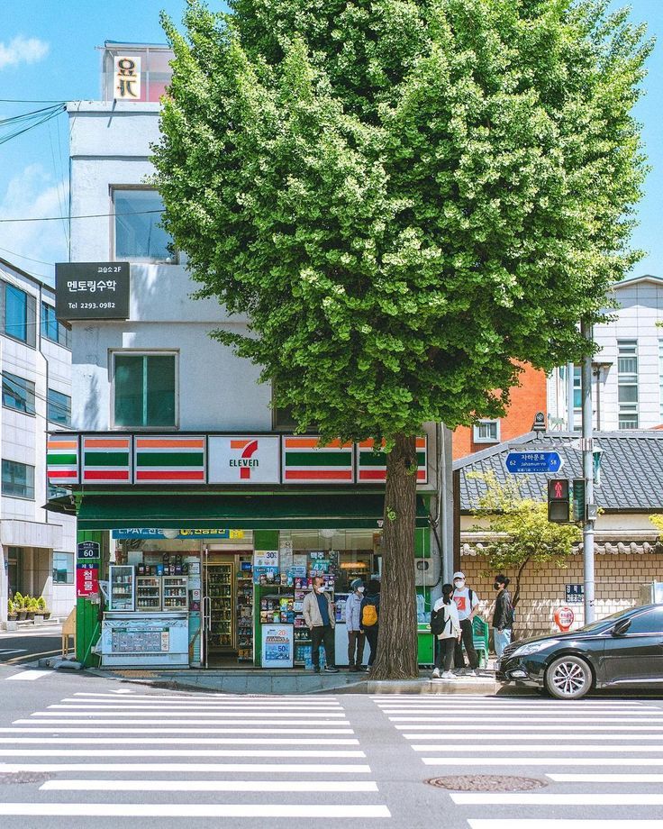 people are standing in front of a gas station on the corner of a city street