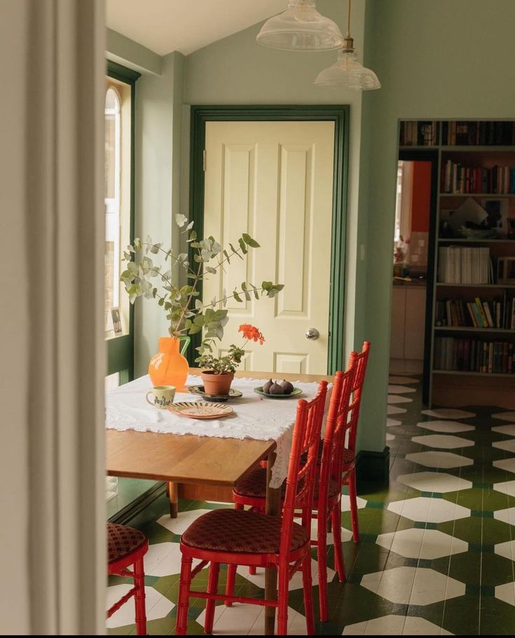 a dining room with green walls and white tile flooring is seen through an open door