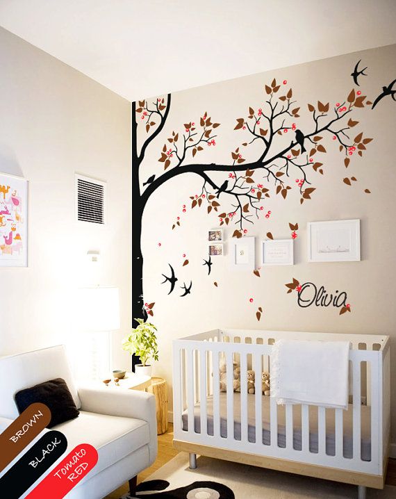 a baby's room with a white crib and tree decal on the wall