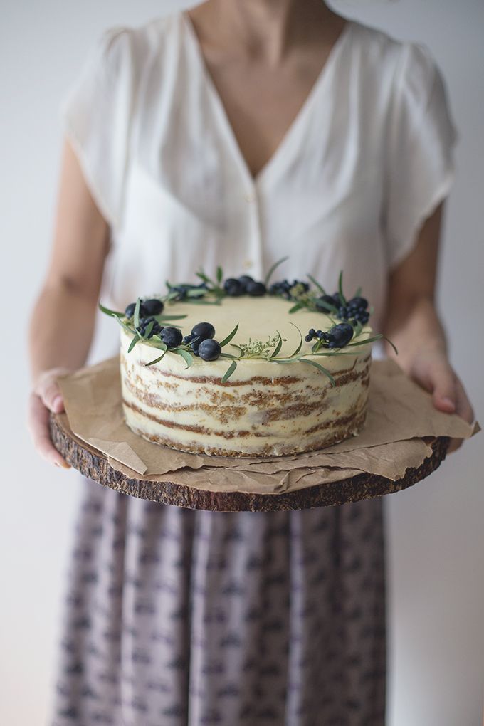 a woman is holding a cake with blueberries on it