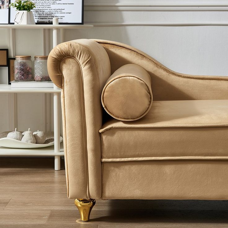 a beige couch sitting on top of a hard wood floor next to a white shelf