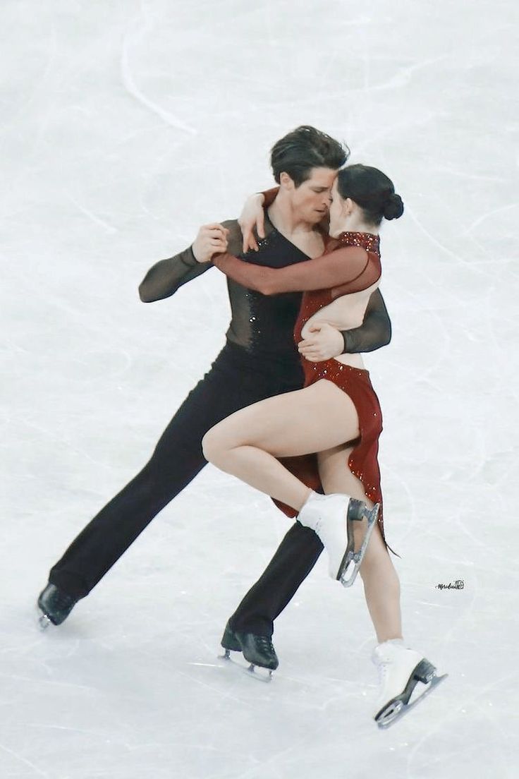 two people in the snow hugging each other while they are performing an ice skating routine