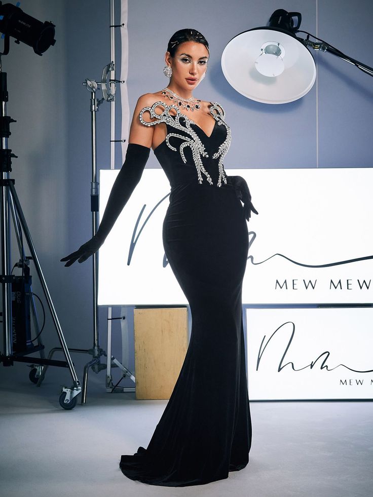 a woman in a black evening gown posing for a photo with a camera behind her