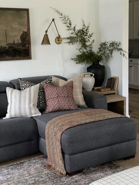 a living room filled with lots of furniture next to a painting on the wall and plants