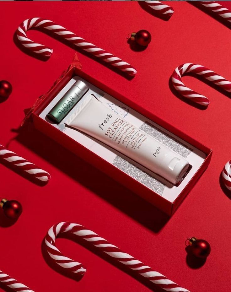 a tube of lotion sitting in a red box surrounded by christmas candy canes