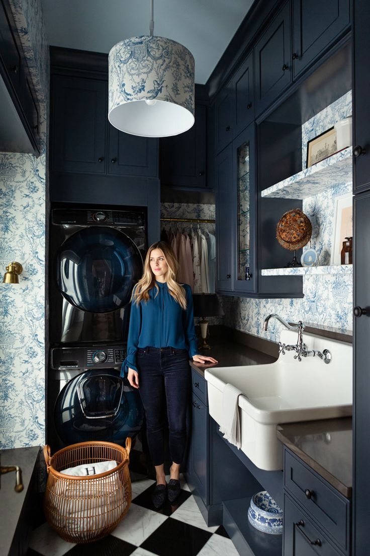 a woman standing in front of a kitchen sink next to a black and white checkered floor