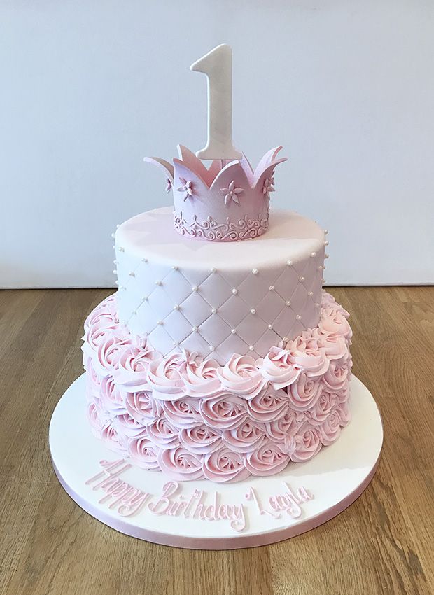 a pink and white birthday cake with a number one on top