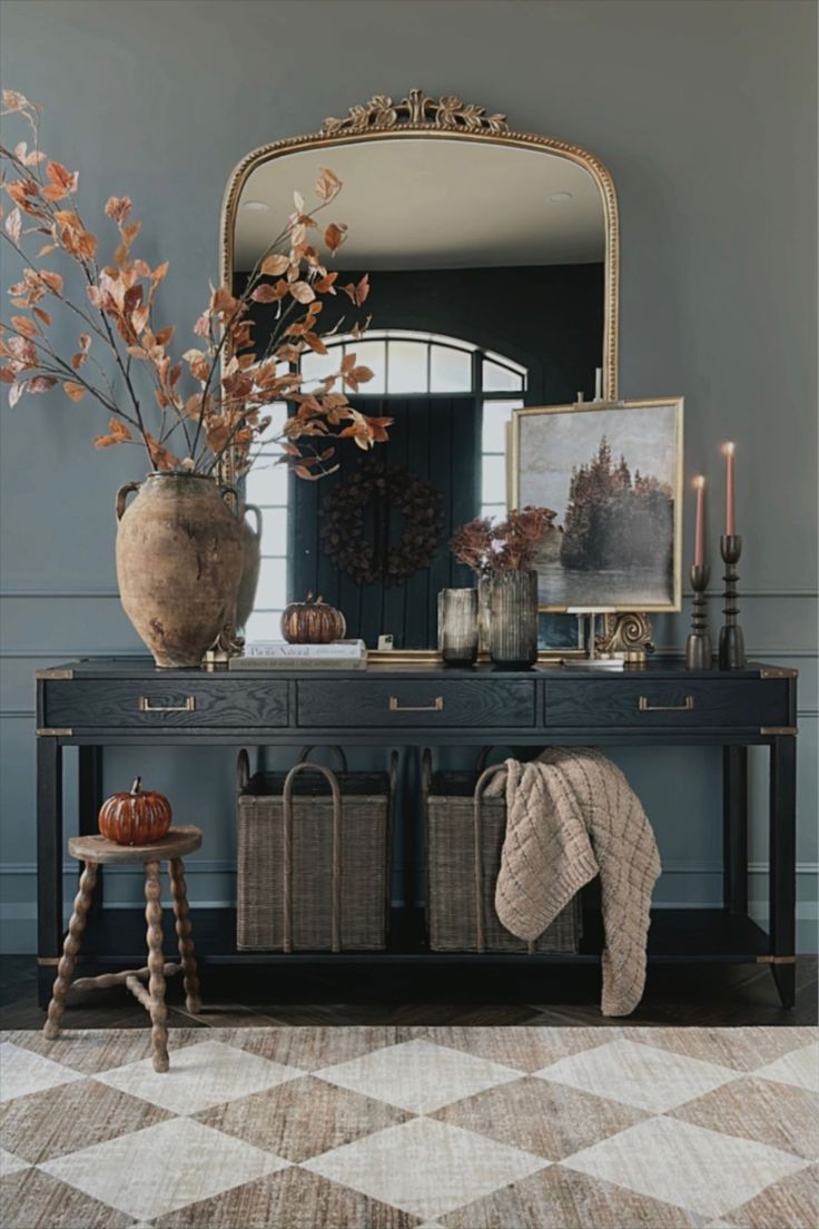 a room with a table, mirror and vase filled with flowers on top of it