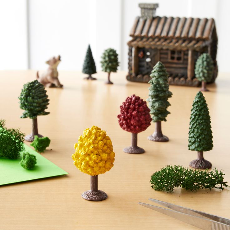 miniature trees are arranged on a table with scissors