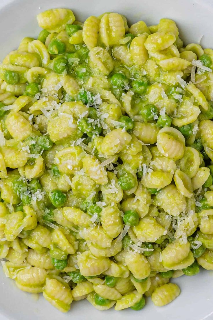 a white bowl filled with pasta and peas