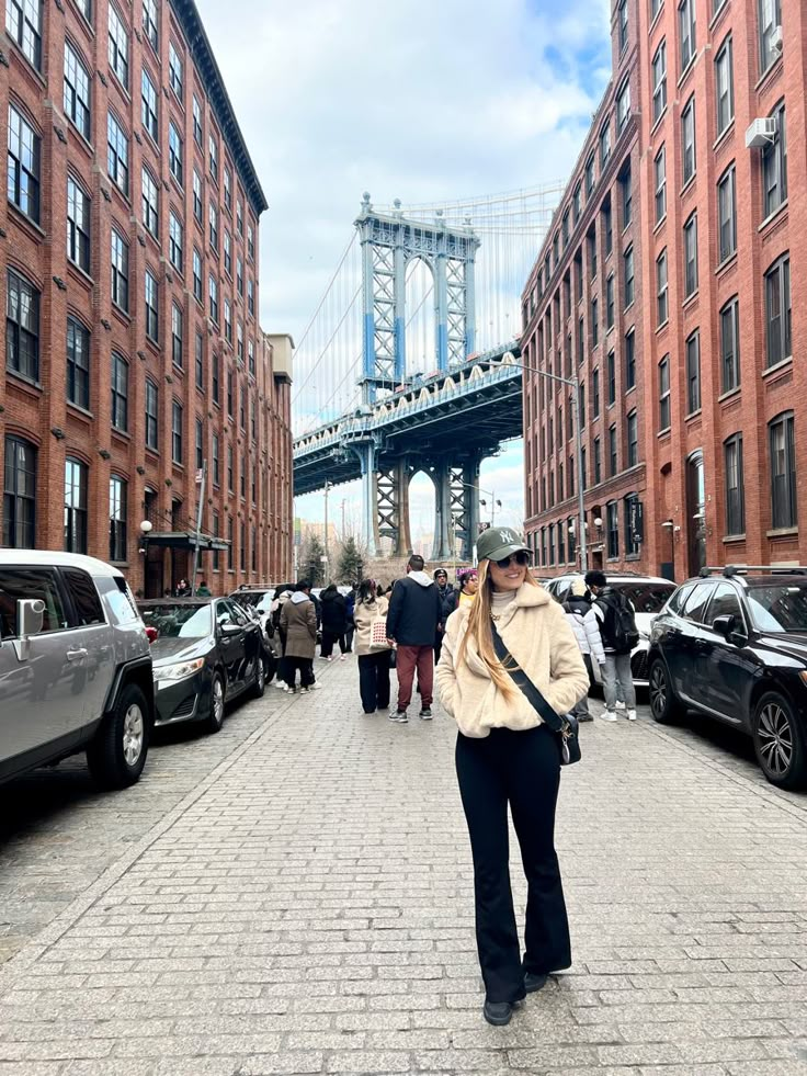 a woman is walking down the street in front of some tall buildings and a bridge