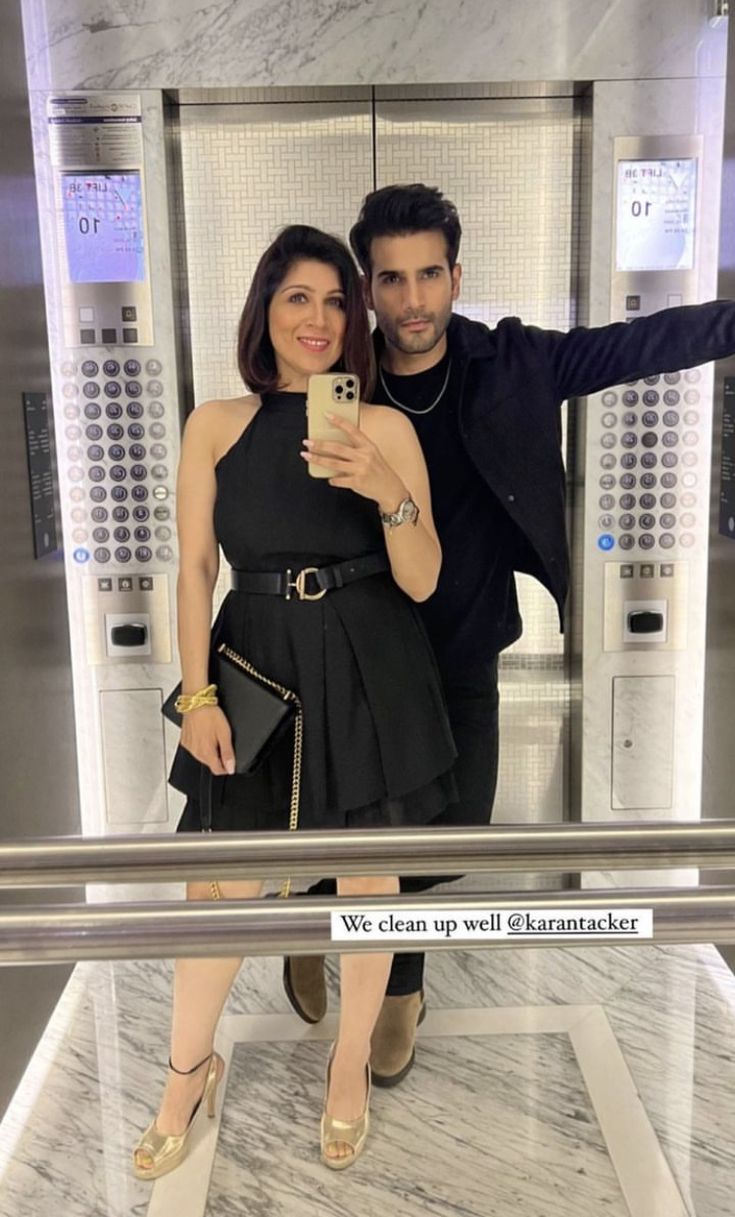 a man and woman taking a selfie in front of an elevator with their cell phone