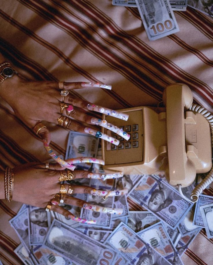 a woman's hands with manicures on top of money and an old telephone