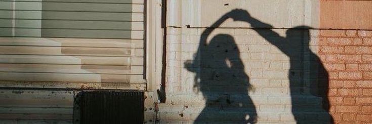 a shadow of a person standing in front of a brick building with a skateboard