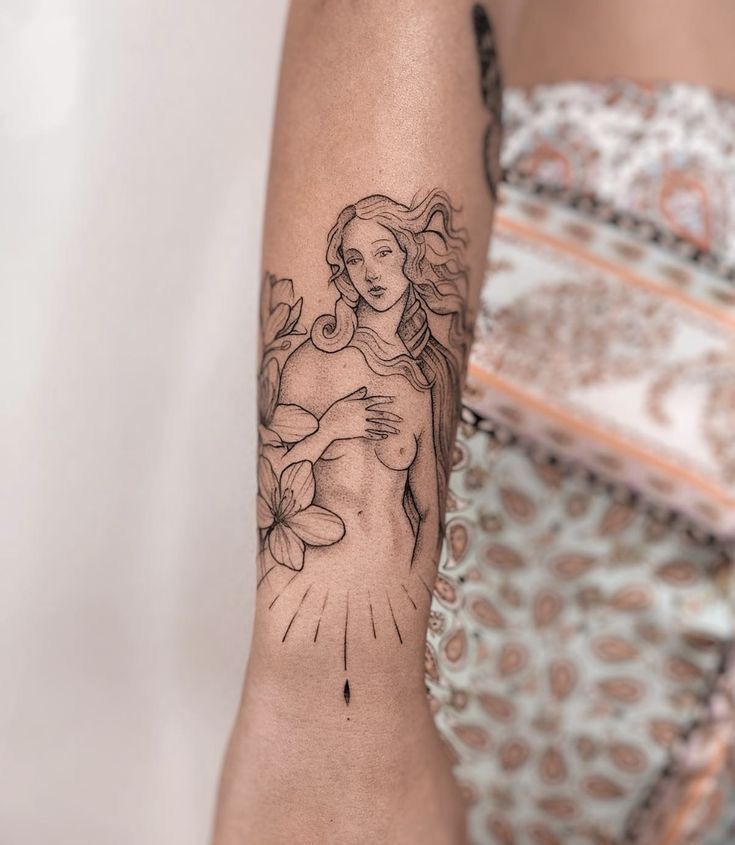 a woman's arm with a tattoo on it and flowers in the foreground