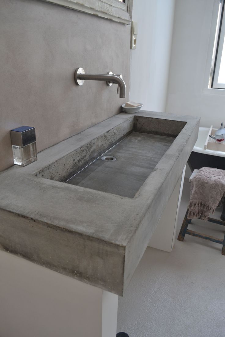 a bathroom sink sitting under a window next to a chair