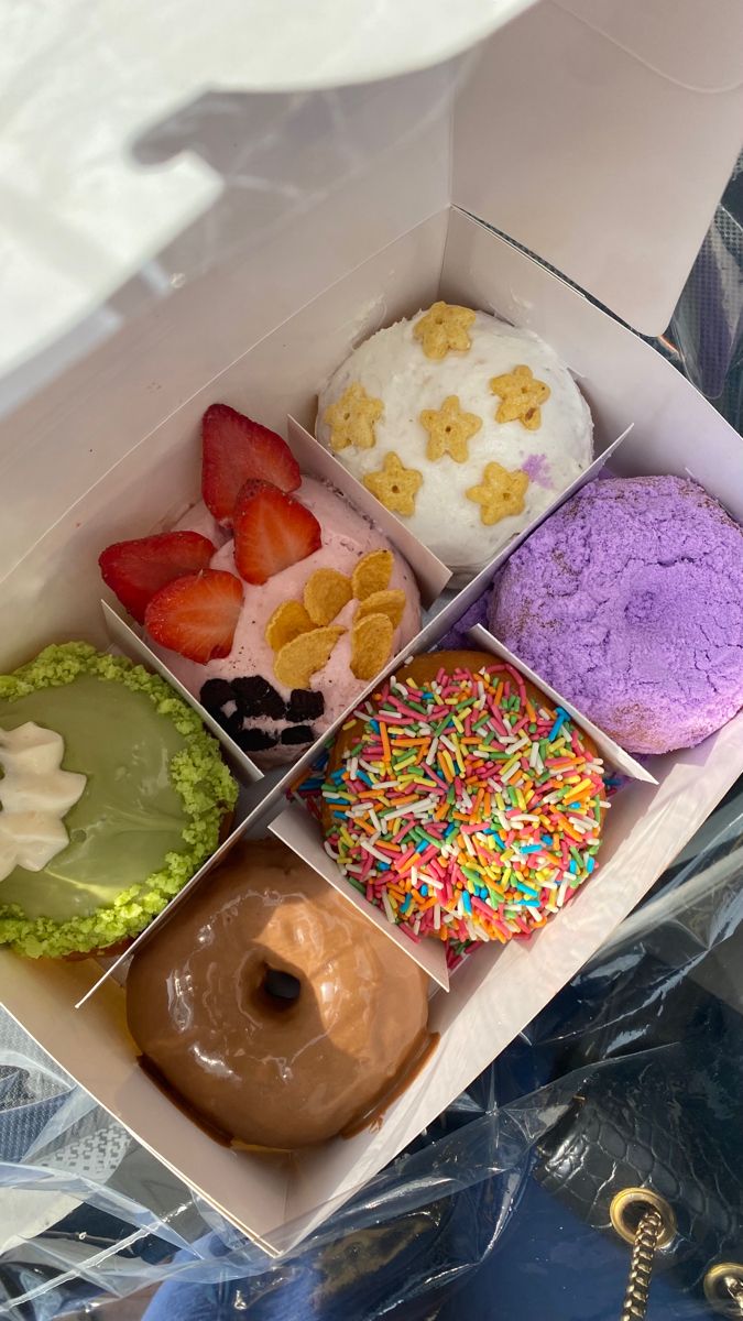 an open box filled with different types of donuts and toppings on top of each other