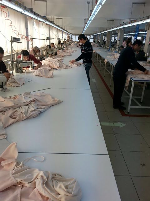 several people working in a factory with lots of white cloths on the tables and floor