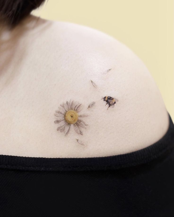 the back of a woman's shoulder with two small flowers on it