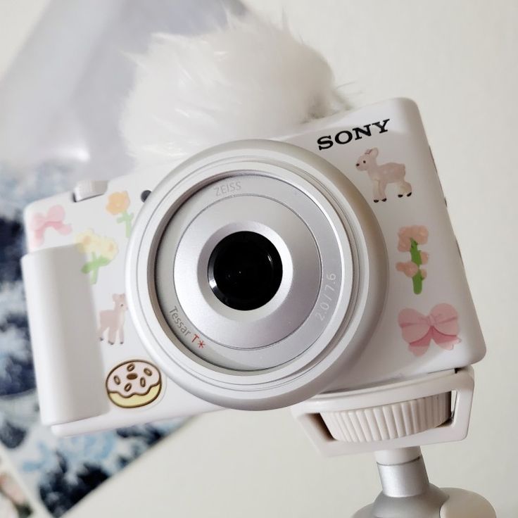 a white camera sitting on top of a tripod next to a stuffed animal toy