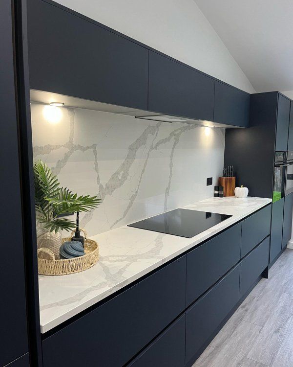 a kitchen with black cabinets and white counter tops, along with a plant on the island