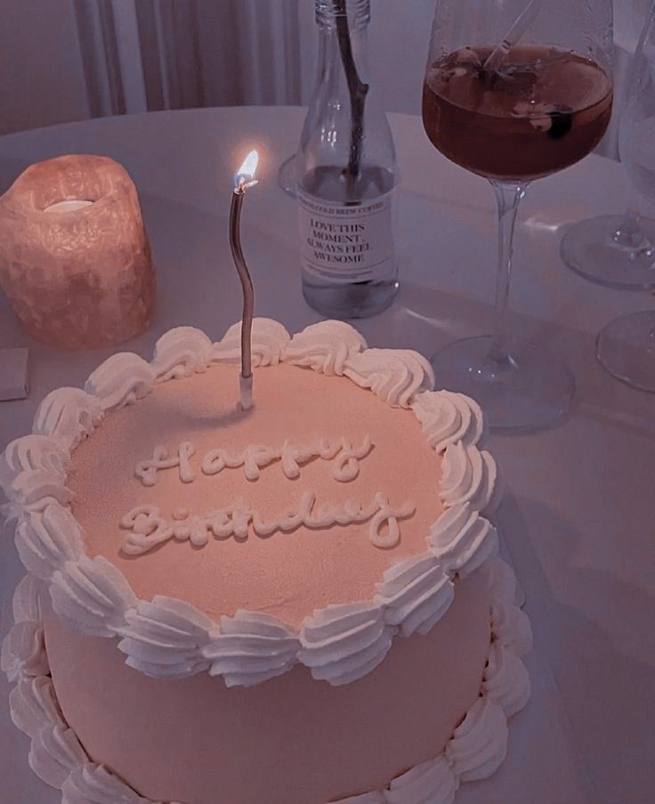 a birthday cake sitting on top of a table next to a wine glass and bottle