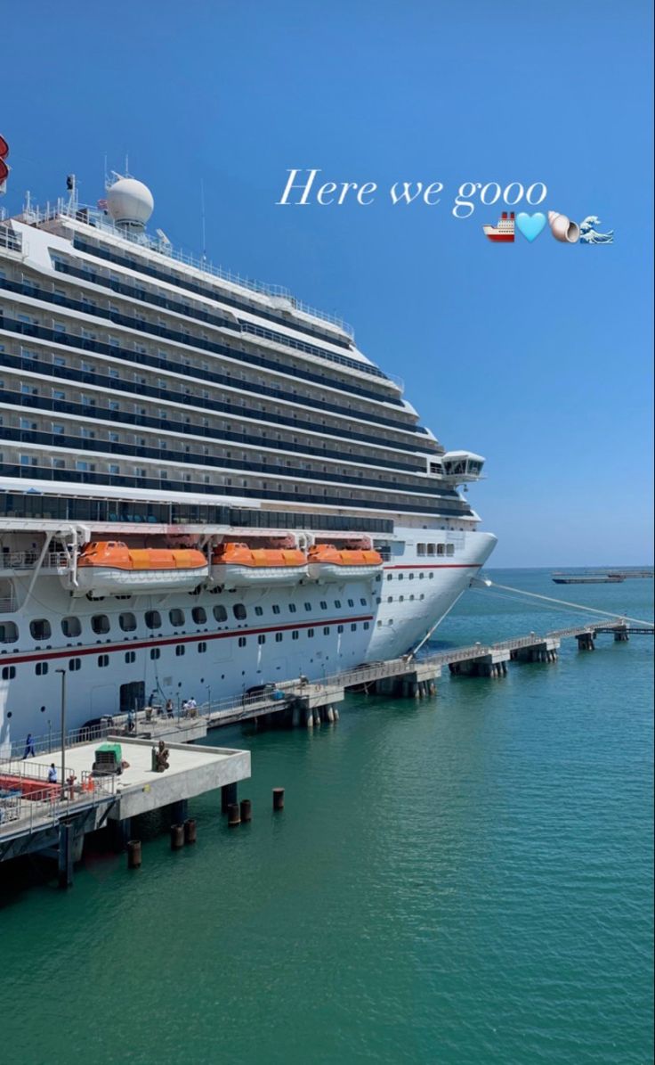 a cruise ship docked at a pier with the words here we go written above it