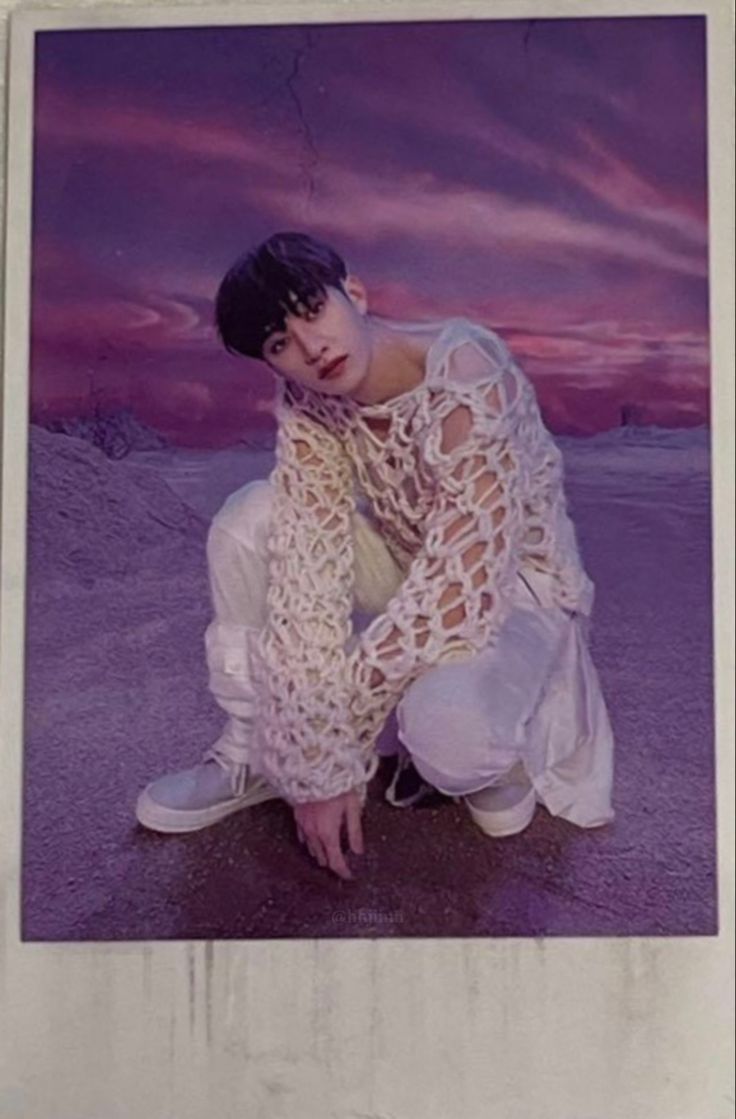 a young man kneeling down in front of a purple sky