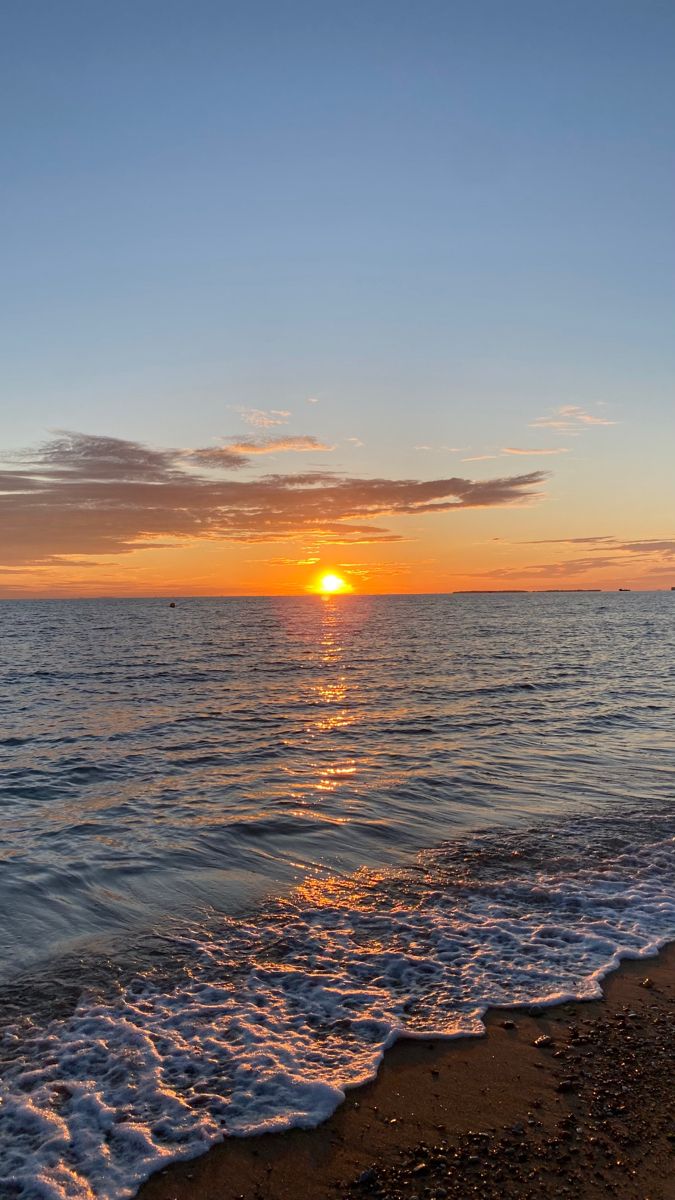 the sun is setting over the water at the beach