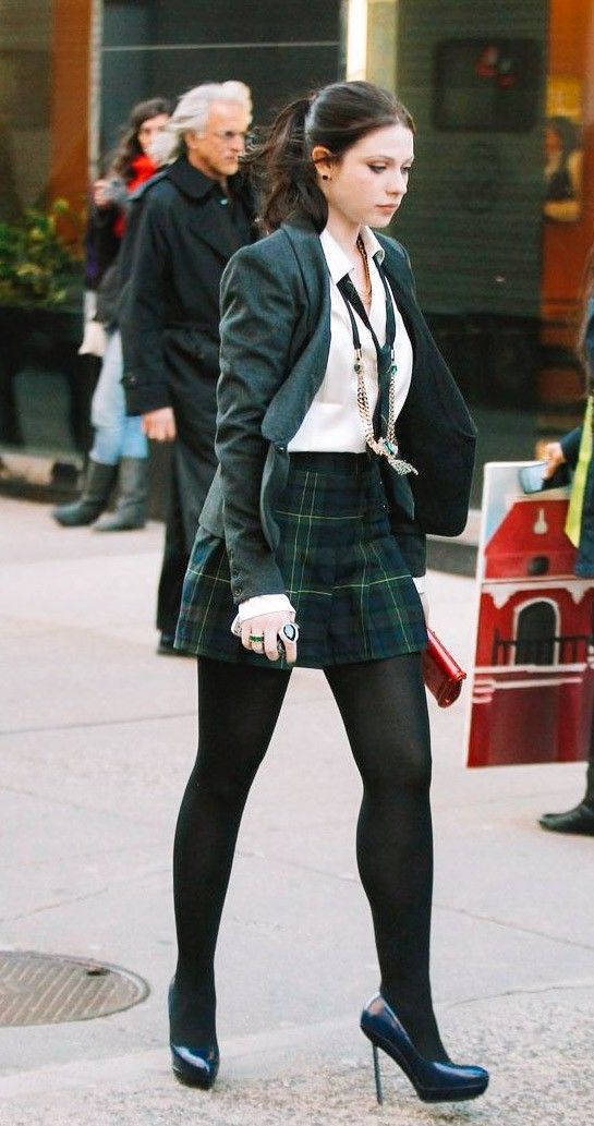 a woman in a skirt and jacket walking down the street