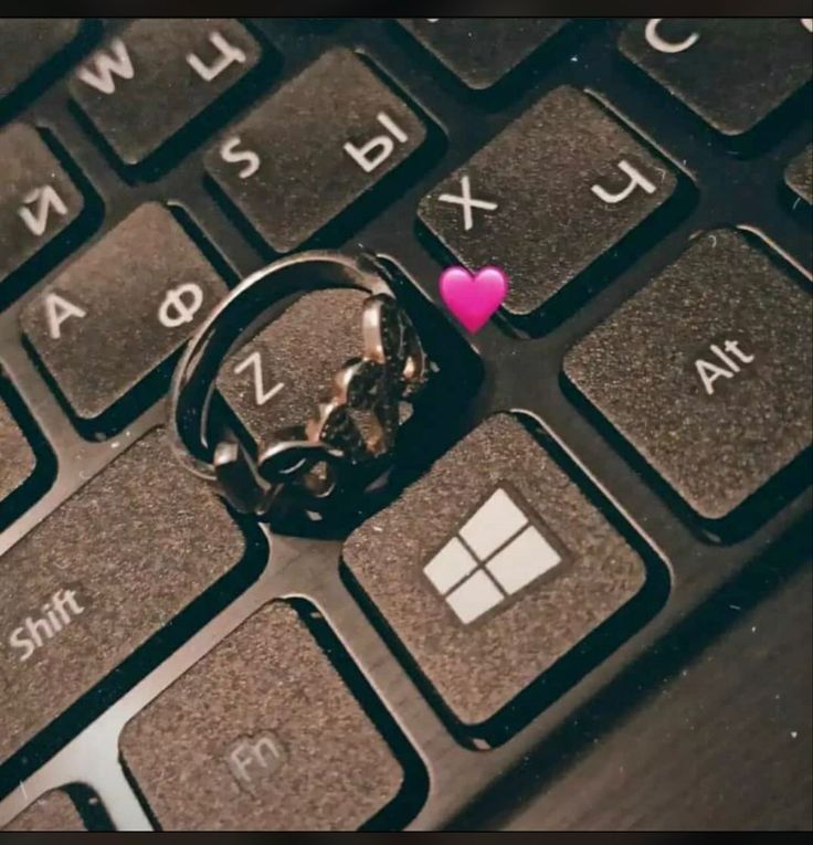 a pink heart sitting on top of a computer keyboard next to a keychain