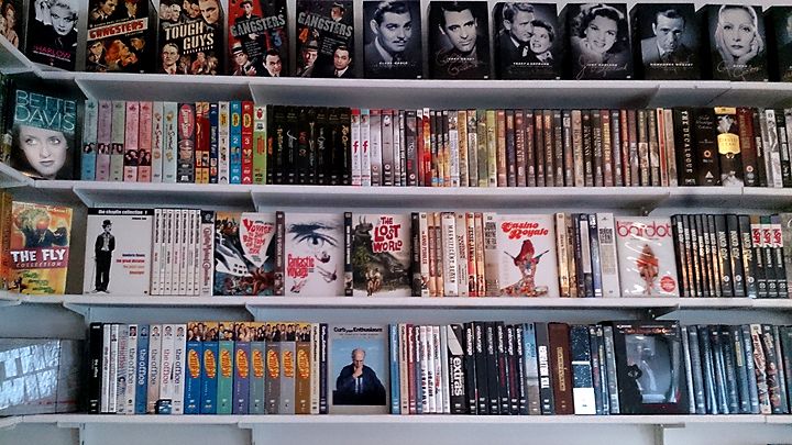 a bookshelf filled with lots of different types of movies on it's shelves