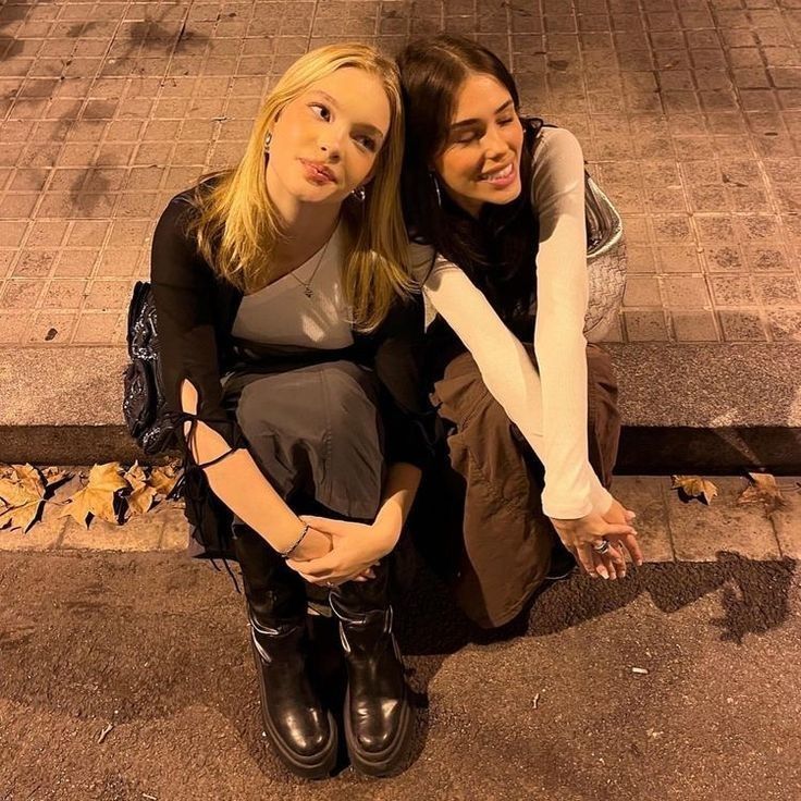 two young women sitting on the ground next to each other