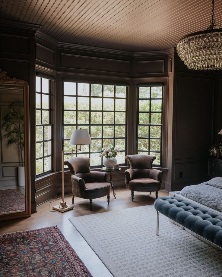 a bedroom with two chairs, a bed and a chandelier hanging from the ceiling