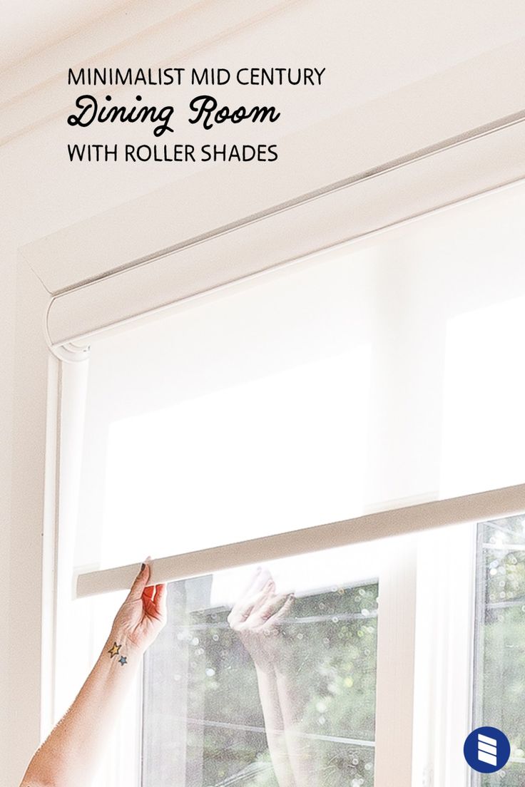 a woman standing in front of a window with her hand on the roller shade rod