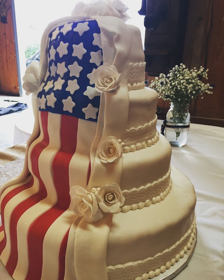 a three tiered cake with an american flag design on the top and flowers on the bottom