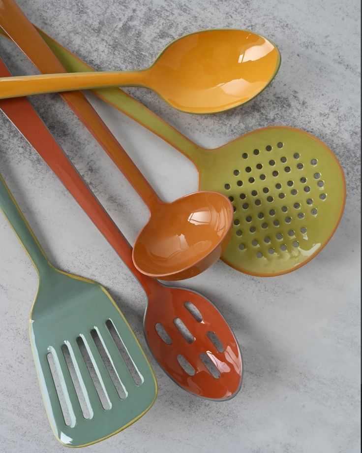 four different colored spoons are lined up next to each other on the counter top