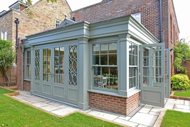 an orangery with glass doors and windows in front of a brick building