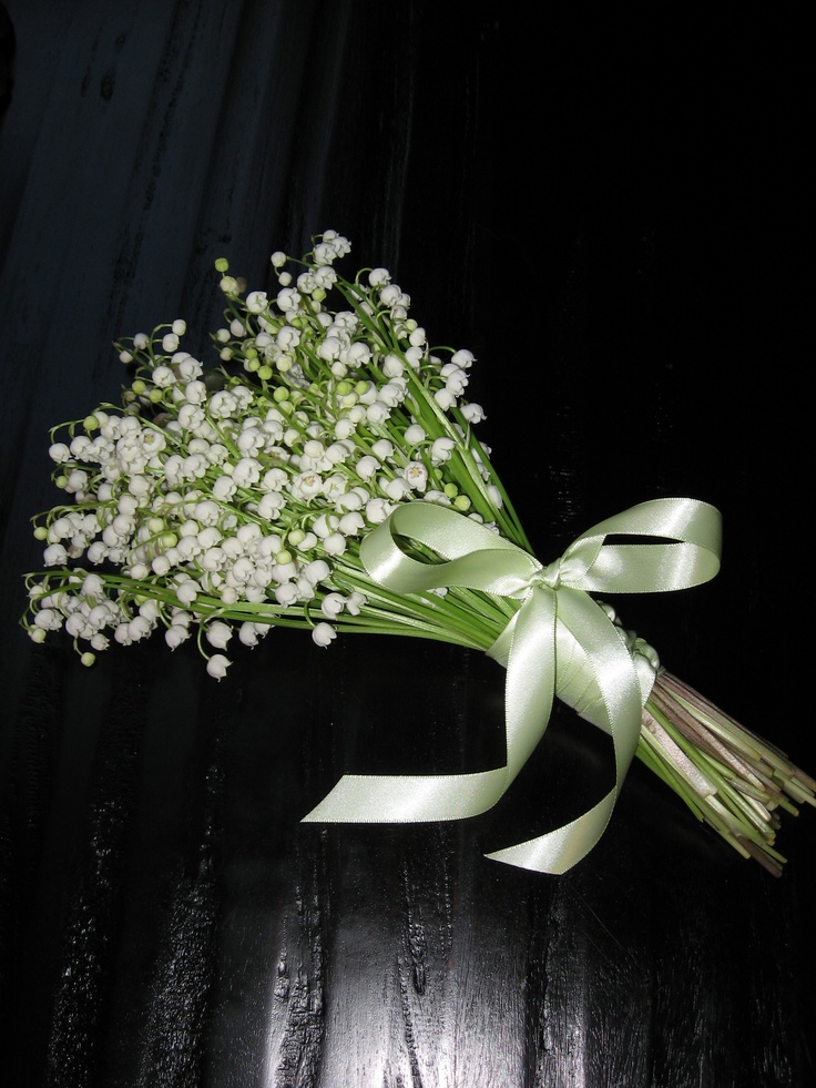 a bouquet of baby's breath tied to a ribbon on a wooden table with dark background