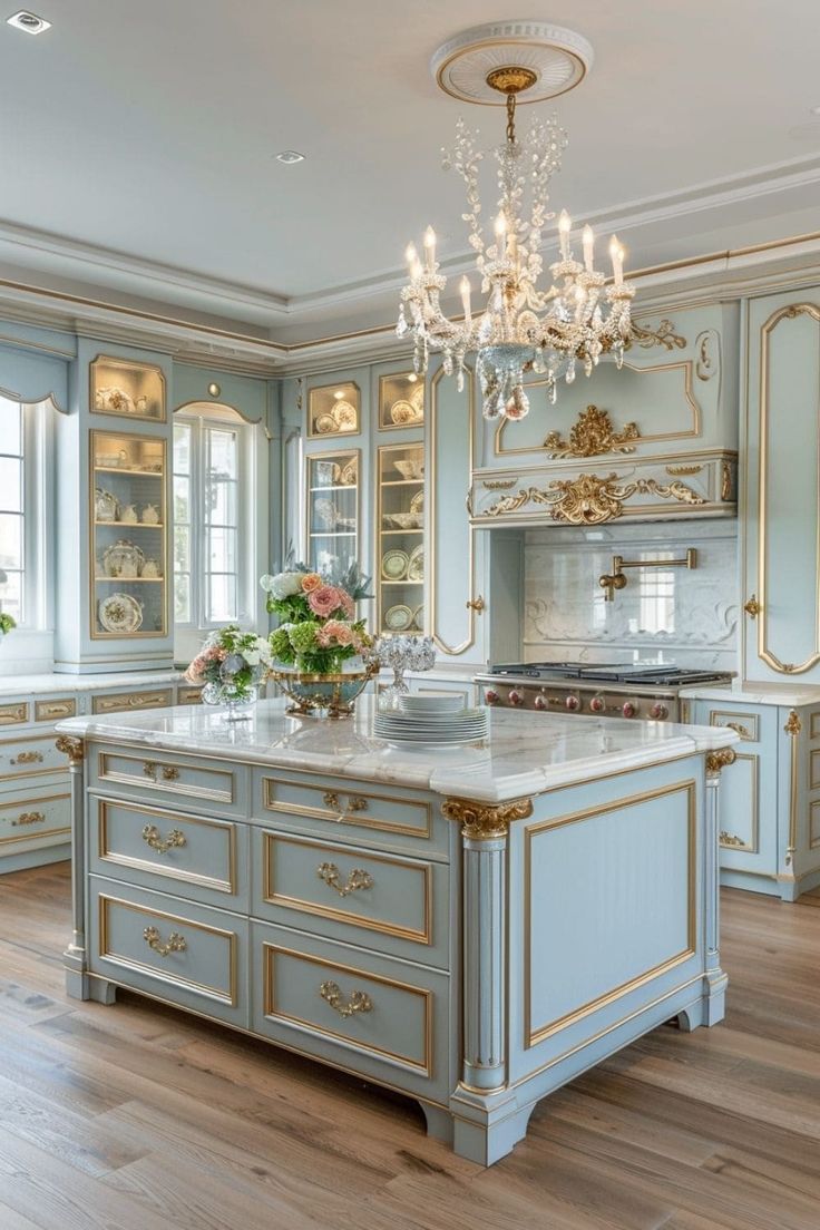 an elegant kitchen with blue cabinets and gold trimmings, chandelier above the island