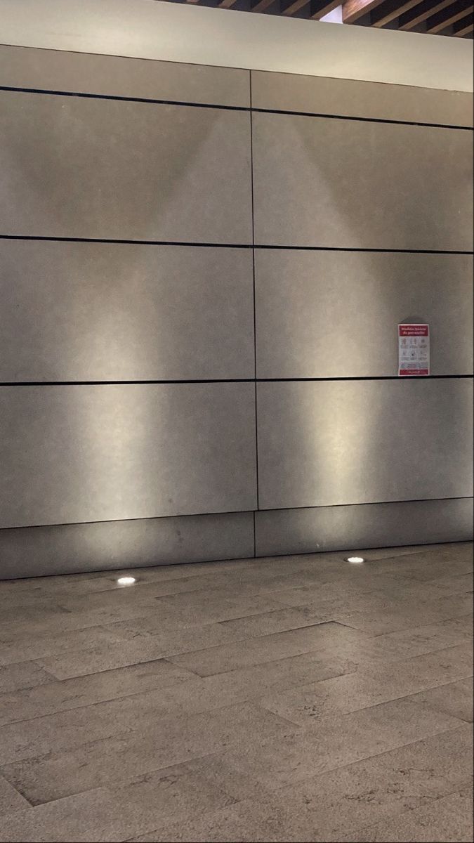 a man riding a skateboard down a sidewalk next to a wall with lights on it