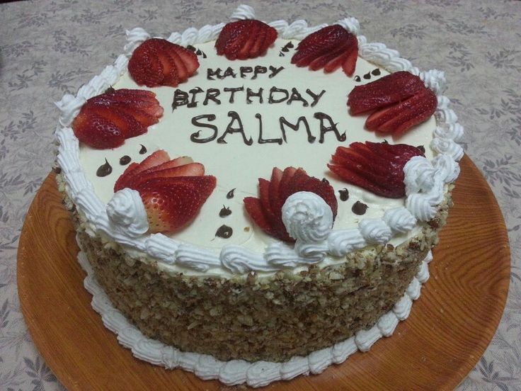 a birthday cake with strawberries on it sitting on a table