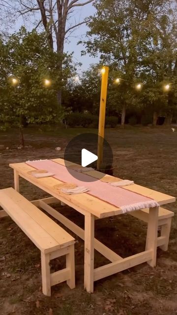 a picnic table and bench with lights in the background