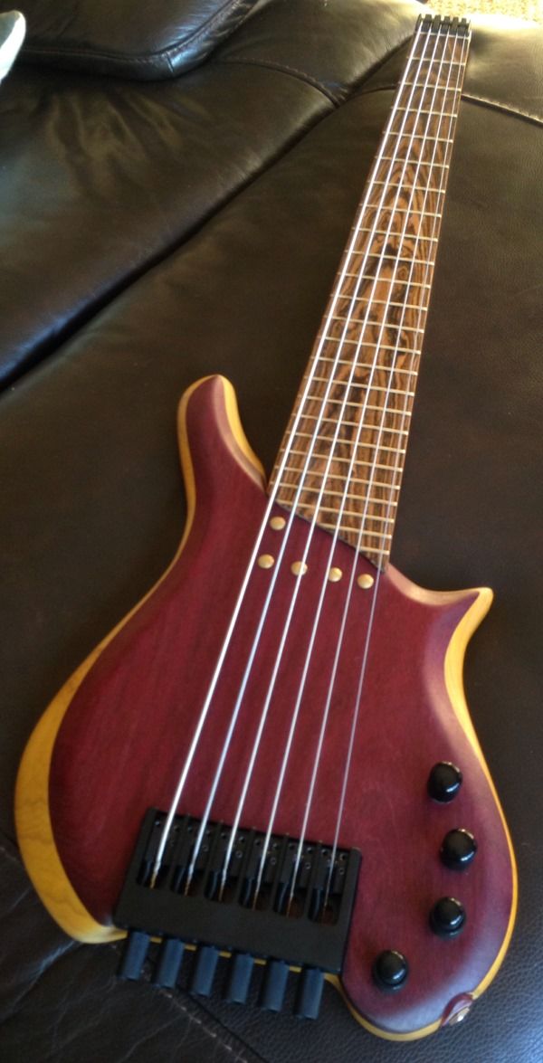 a red and yellow bass guitar sitting on top of a couch