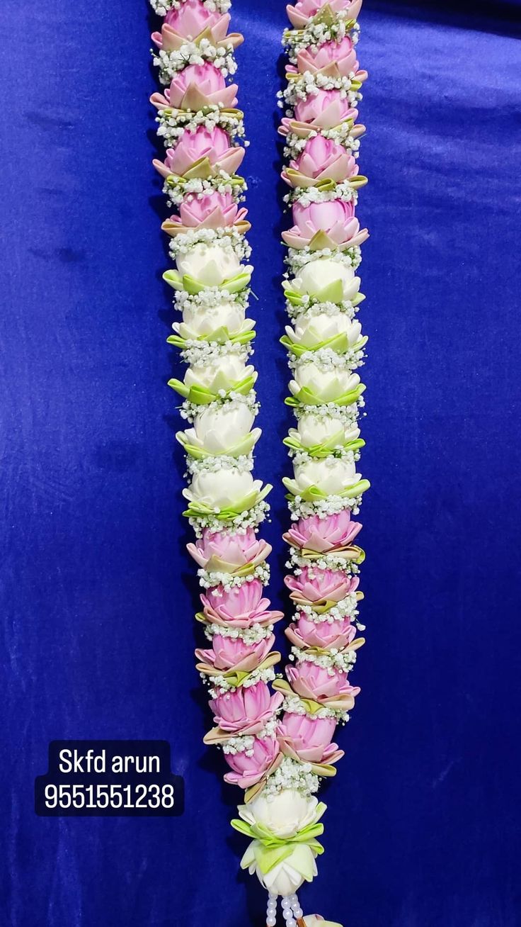 two pink and white flowers are attached to the side of a blue tableclothed backdrop