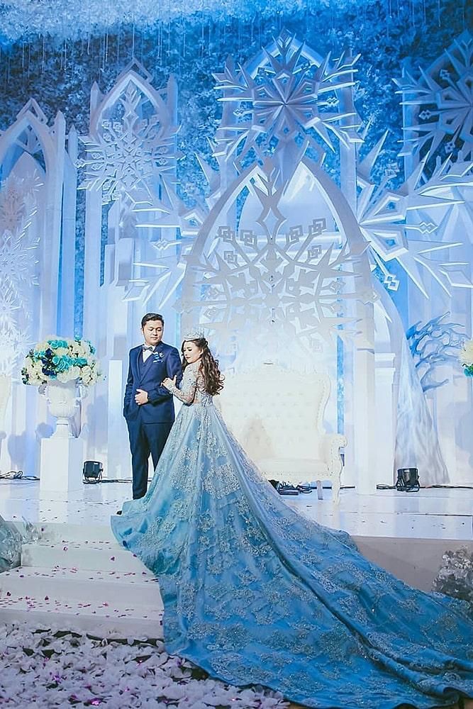 a bride and groom are standing in front of an ice - covered backdrop with snowflakes