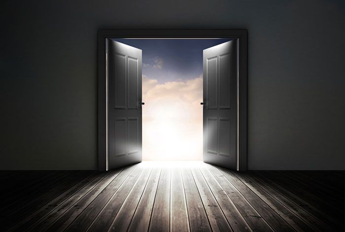 an open door leading to a bright blue sky with white clouds in the middle and light coming from it