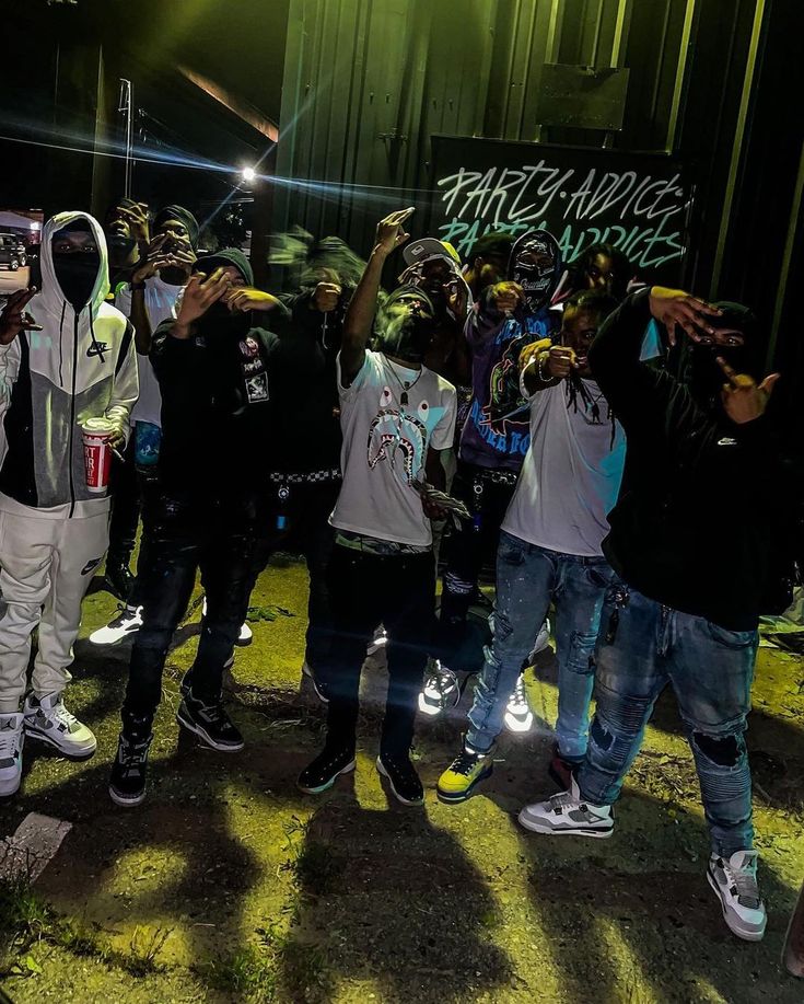 a group of young men standing next to each other in front of a wall with graffiti on it