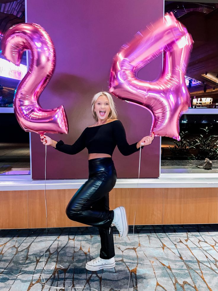 a woman posing for a photo with balloons in the shape of the number twenty two