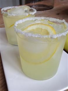 two glasses filled with lemonade sitting on top of a white plate